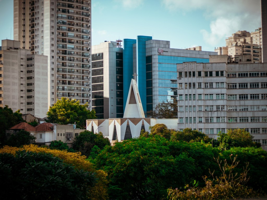 Bairro de São Paulo com prédios residenciais, igreja moderna e áreas verdes ao redor.